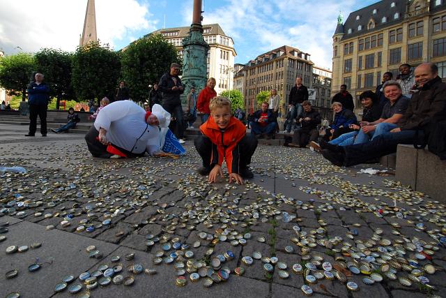 There is apparently some tradition where on their 30ies birthday guys have to clean up bier bottle caps in public - unless/until he finds a women/girl who kisses him. The kid jumped in the picture.